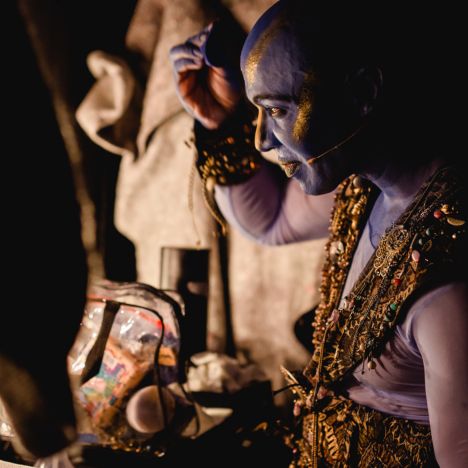 Ein Darsteller als Genie schminkt sich im Bühnenbereich.